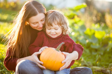 Mother and child choosing pumpkins for jack-o-lantern.