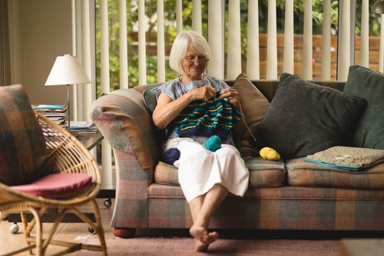 Senior woman knitting wool in living room