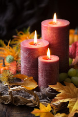 Thanksgiving dinner concept. Lit candles with pumpkins, grapes, autumn leaves and fall decorations