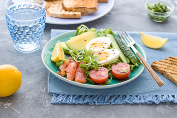 Healthy salad with avocado, corn salad, smoky salmon, eggs and tomatoes for breakfast. Close up