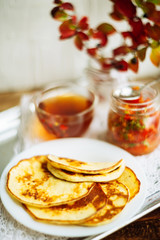 Home-made breakfast or brunch: american style pancakes served with berries and sugar powder on vintage metal tray with a cup of black tea