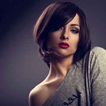 Sexy expressive makeup woman with short bob hair style, red lipstick on dark shadow background. Closeup toned portrait.