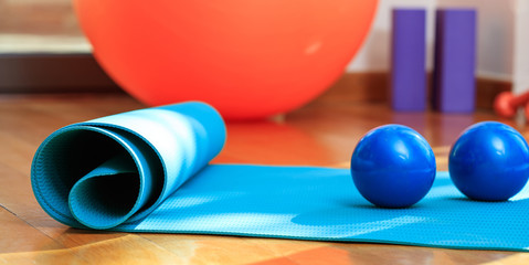 Yoga mat and exercise weights on wooden floor