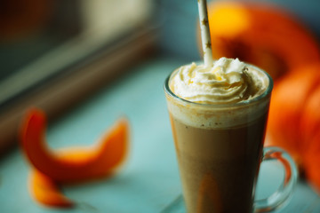 Pumpkin smoothie, spice latte with whipped cream on top on a turquoise wooden background. copy space