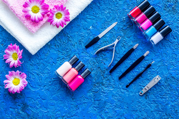 Obraz na płótnie Canvas Manicure in beauty salon. Tools for manicure, nail polishes and towels on blue desk top view