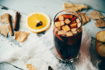 Fototapeta na wymiar Hot mulled wine in a glass with orange slices, anise and cinnamon sticks, star cookies on vintage wood table. Christmas or winter warming drink with recipe ingredients around