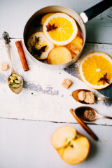 Fototapeta na wymiar A glass of hot mulled wine, spices, cinnamon, star anise, brown sugar and nuts on a wooden board