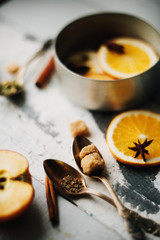A glass of hot mulled wine, spices, cinnamon, star anise, brown sugar and nuts on a wooden board