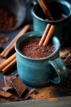 Cup of hot chocolate with a stick of cinnamon and the flakes of grated dark chocolate