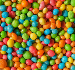 Fototapeta na wymiar Colorful background of bright candy small round forms. Abstract sweets with raisins or nuts stuffing