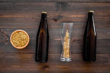 Preparing beer. Barley near beer bottle and glass on wooden background top view