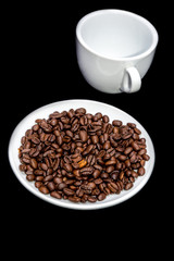 Coffee beans in a saucer with a cup.