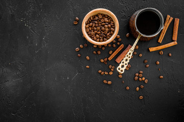 Obraz na płótnie Canvas Brew coffee in turkish coffee pot. Black background top view copyspace