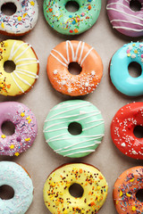 Tasty donuts with sprinkles on paper background