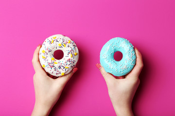 Female hands holding sweet donuts with sprinkles