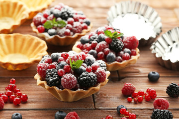 Tasty tartlet with berries and powdered sugar on brown wooden table