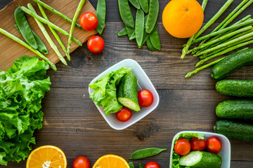 Healthy meal in containers. Salad with tomato, cucumber, orange in containers on wooden background top view