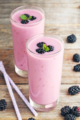 Blackberries yogurt in glasses on grey wooden table