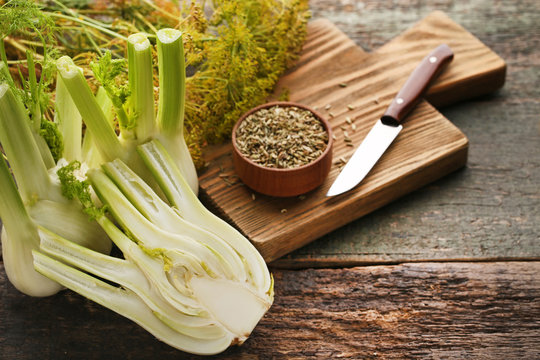 Ripe fennel bulbs and dry seeds in bowl on wooden table
