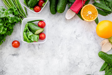 Vegearian lunch. Vegetables tomato, cucumber, asparagus, salad, orange on grey background top view copyspace