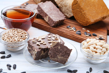 Tasty halva with peanuts and sunflowers seeds on wooden table