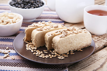 Tasty slices of halva in plate on wooden table