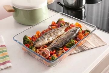 Foto auf Glas Baking tray with tasty fish and vegetables on kitchen table © Africa Studio