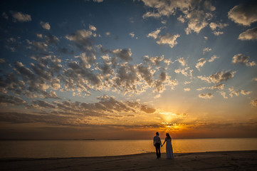 Bride and groom, newlyweds, honeymoon on the beach sunset sun