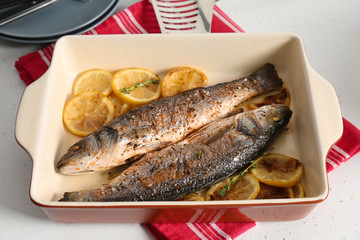 Baking tray with tasty fish on kitchen table