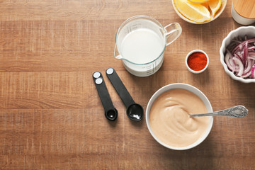 Bowl with tasty fish taco sauce and ingredients on wooden table