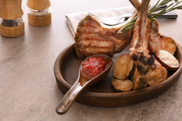 Plate with delicious ribs and potatoes on table