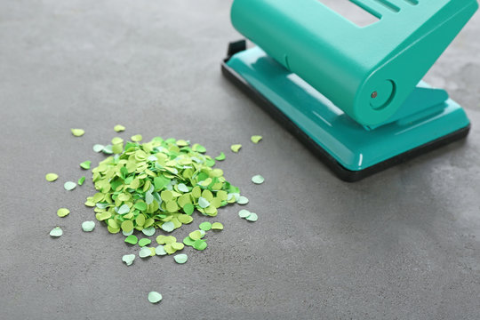 Green Hole Punch And Paper Confetti On Gray Table