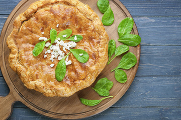 Tasty pie with spinach on wooden board