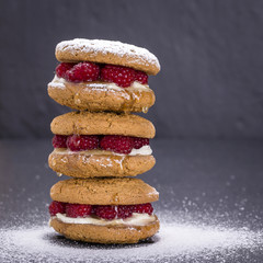 Oat cookies with raw raspberry, honey and soft cheese on the background of black slate , close up