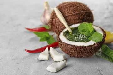 Half of coconut with chutney mint sauce on table