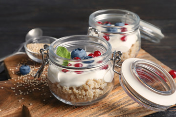 Tasty quinoa with berries in jars on wooden board