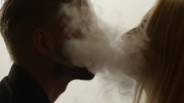 Woman gives smoke kiss to man. Vape culture. Seamless loop