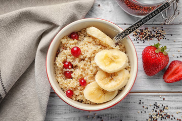 Ramekin with tasty quinoa on wooden table