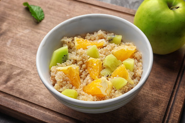 Tasty quinoa with fruits in bowl on  wooden board