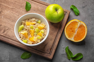 Tasty quinoa with fruits in bowl on  wooden board