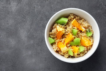 Tasty quinoa with fruits in bowl on  table