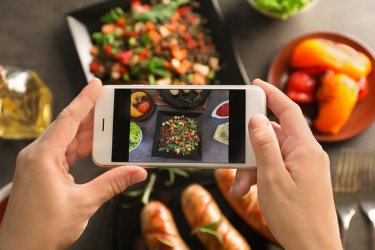 Female blogger taking photo of food with smartphone indoors