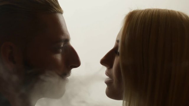 Woman gives smoke kiss to man. Vape culture