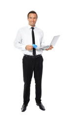 Fototapeta na wymiar Young businessman holding credit card while using laptop on white background
