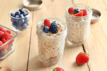Jars of delicious chia seed pudding with berries on table