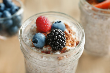 Jar of delicious chia seed pudding with berries on table, close up