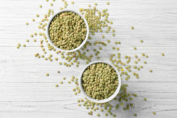 Bowls with green lentils on wooden table