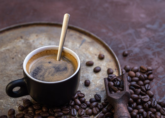 Cup of coffee on rustic background with coffee beans around.