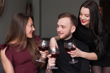 Female seduction at company party. Love triangle. Pleasant conversation, male surrounded by beautiful women with wine. Girl rivalry, romantic background