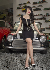 Fototapeta na wymiar girl in a black dress is sitting on the hood of a retro car